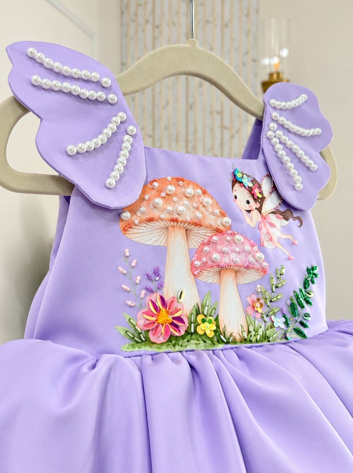 Close-up of the lavender Duchess Satin birthday dress bodice with fairy and mushroom artwork, pearl accents and colourful floral embellishments.