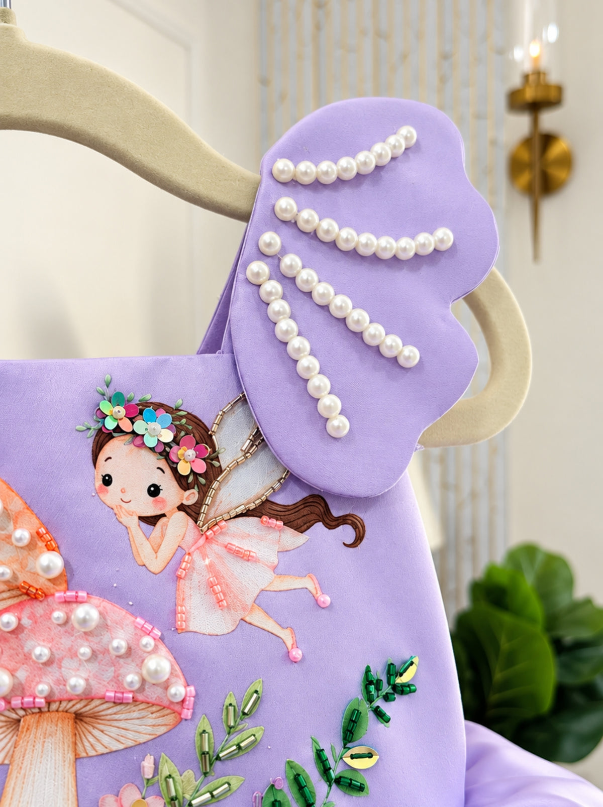 Detailed view of the lavender fairy dress shoulder panel decorated with curved rows of white pearls and a whimsical fairy bodice.