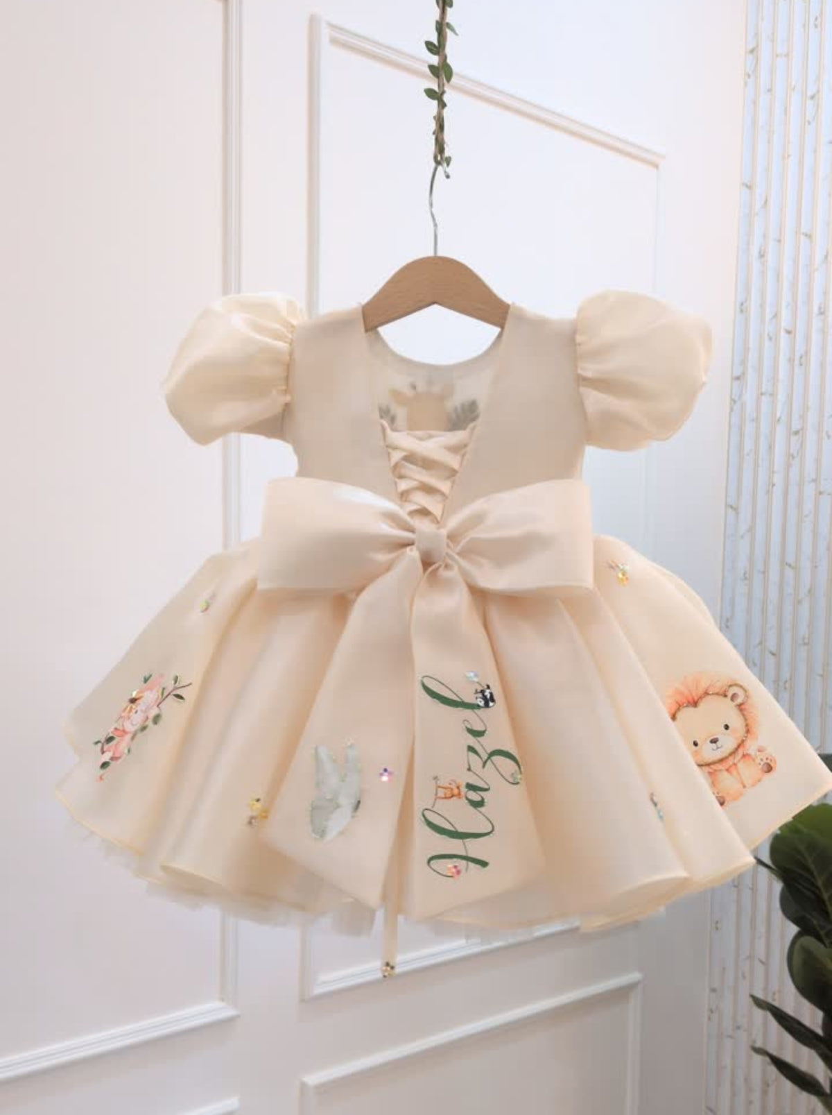 Back view of cream personalized safari birthday dress with oversized bow and name detail