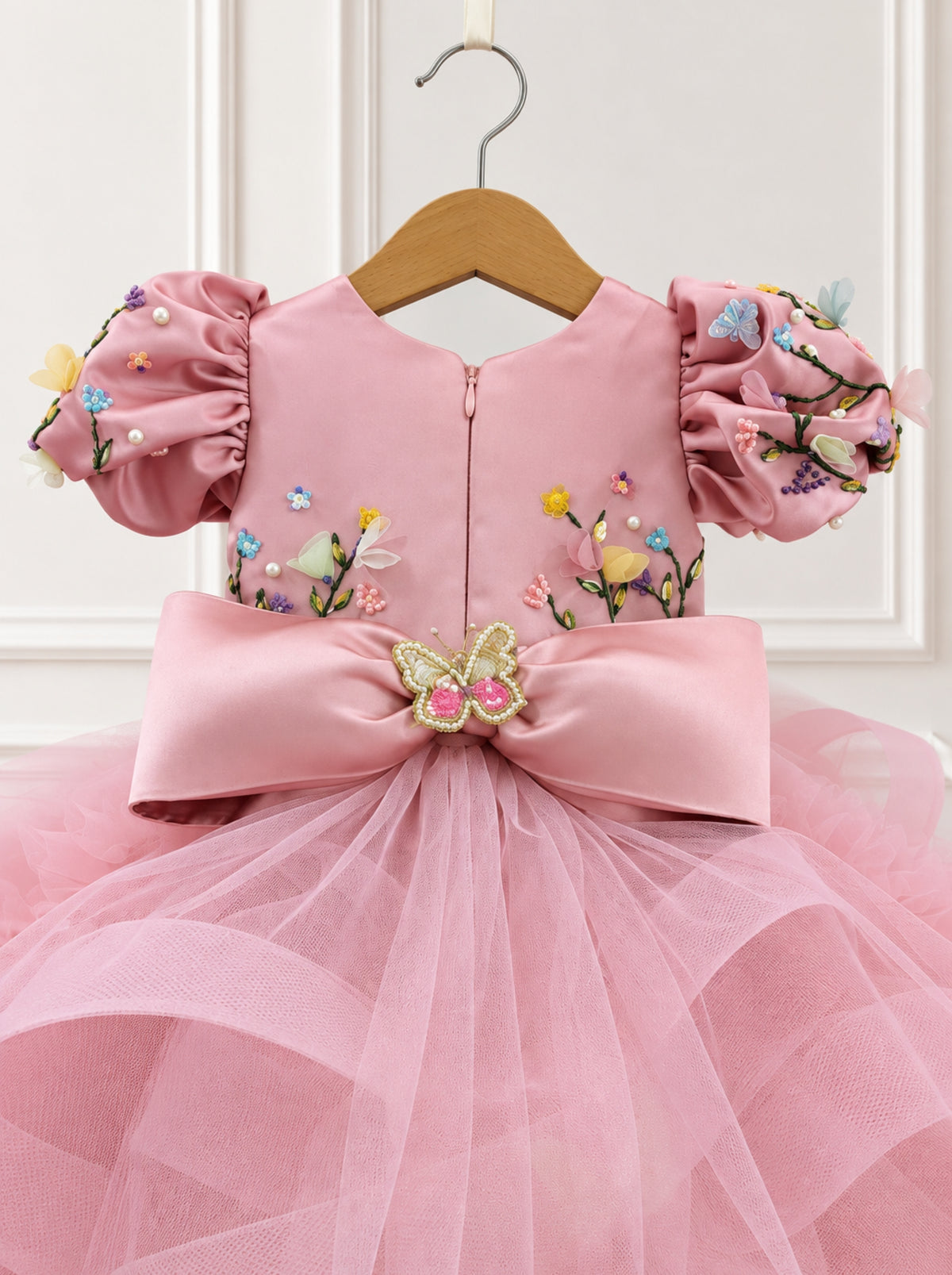 Close-up of hand embroidered pink satin bodice and floral puff sleeve on girls dress