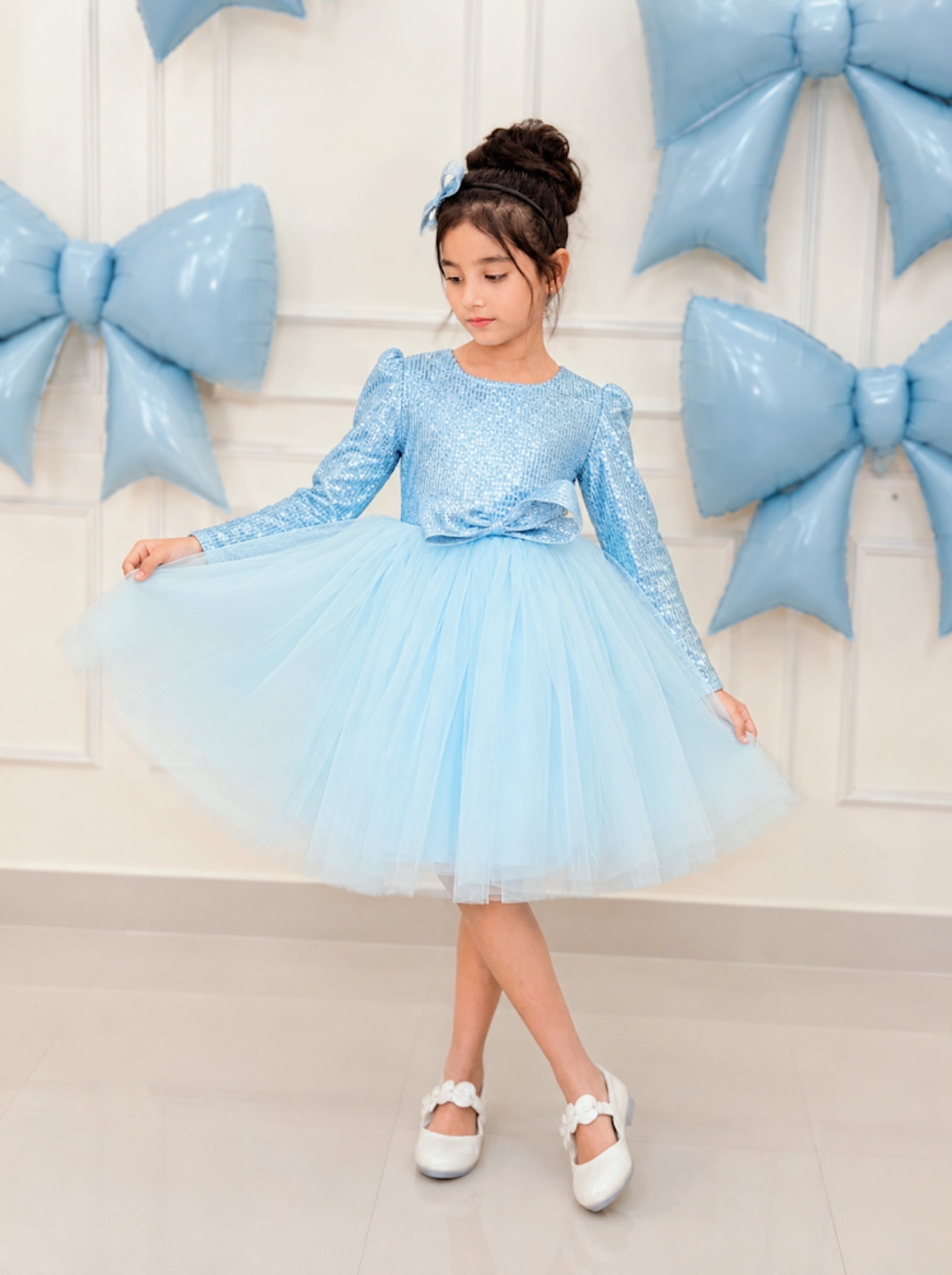 Child wearing powder blue sequin tulle dress with satin bow and matching hair accessory, luxury flower girl outfit.
