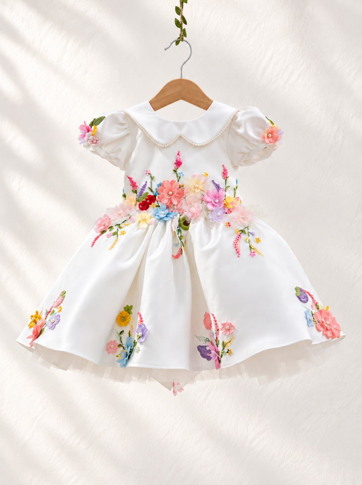 Close-up of 3D floral embroidery on white girls couture dress