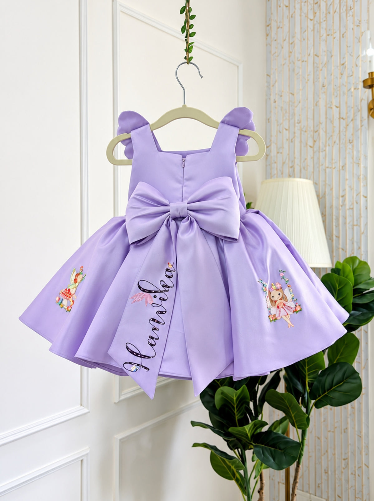 Back view of the lavender girls' birthday dress showing its oversized satin bow, full gathered skirt and decorative fairy details.