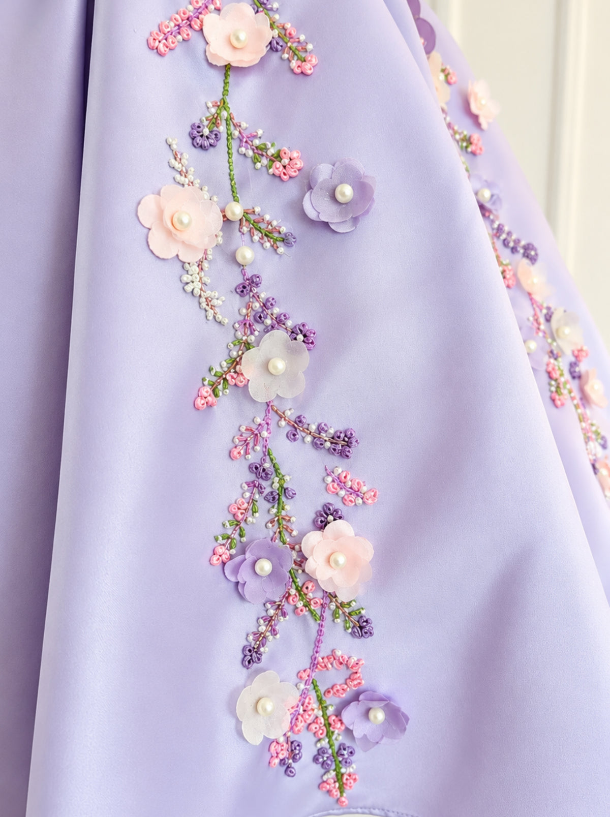 Close-up of floral embroidery and 3D flower embellishments on a lavender girls dress